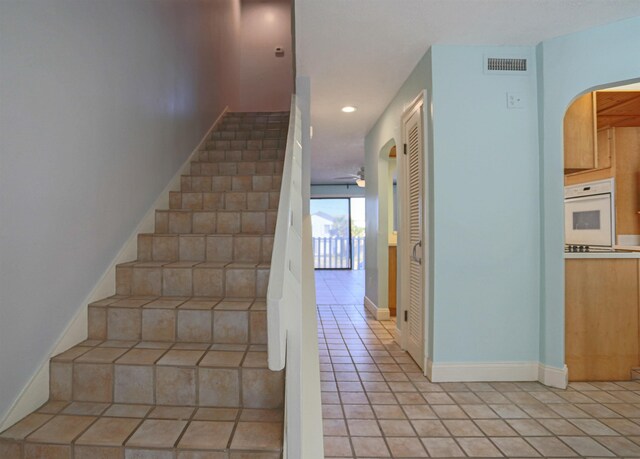 stairs with tile patterned floors and ceiling fan