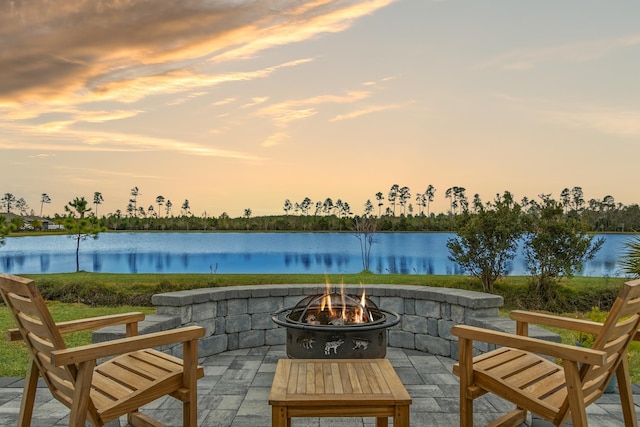 patio terrace at dusk featuring a water view and a fire pit