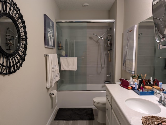 full bathroom with a textured ceiling, vanity, toilet, and bath / shower combo with glass door