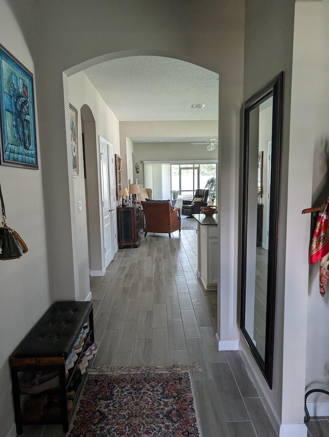 hallway with a textured ceiling and hardwood / wood-style flooring