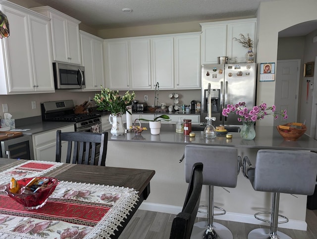 kitchen featuring a kitchen breakfast bar, white cabinetry, dark wood-type flooring, and stainless steel appliances