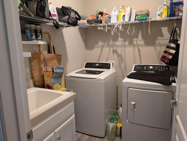 washroom with cabinets, light hardwood / wood-style floors, washer and clothes dryer, and sink