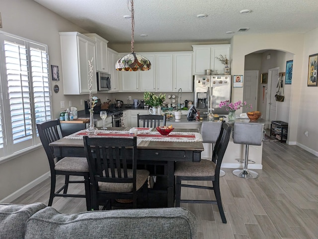 dining area with light hardwood / wood-style floors and a textured ceiling