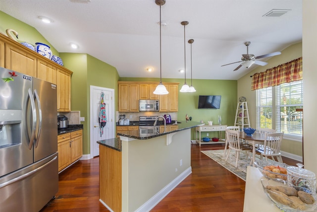 kitchen with dark hardwood / wood-style flooring, hanging light fixtures, appliances with stainless steel finishes, and vaulted ceiling