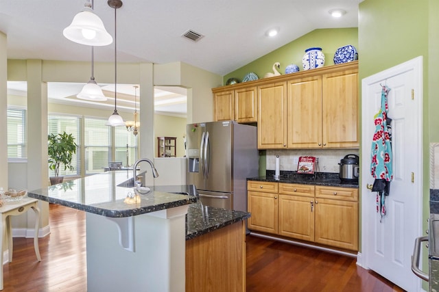 kitchen featuring dark wood-type flooring, hanging light fixtures, stainless steel fridge, dark stone counters, and lofted ceiling