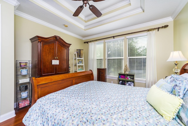 bedroom featuring dark wood-type flooring, a raised ceiling, ceiling fan, and crown molding