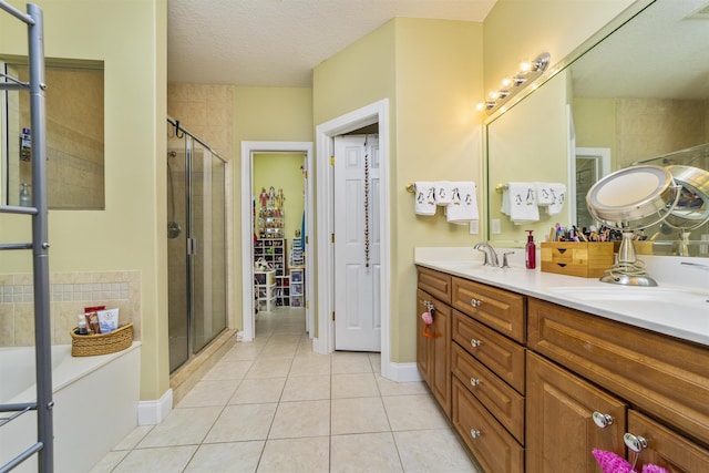 bathroom with tile patterned floors, vanity, an enclosed shower, and a textured ceiling