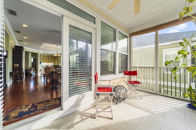 sunroom featuring ceiling fan with notable chandelier