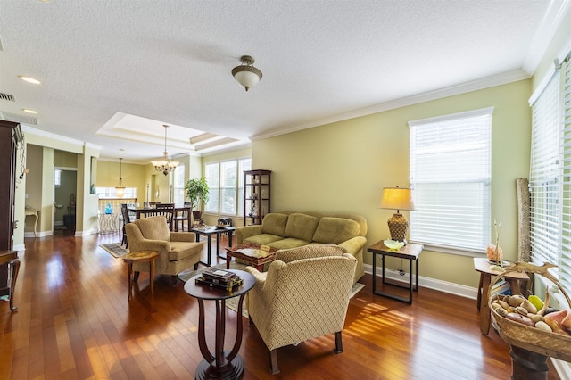 living room with crown molding, dark hardwood / wood-style flooring, a textured ceiling, and an inviting chandelier