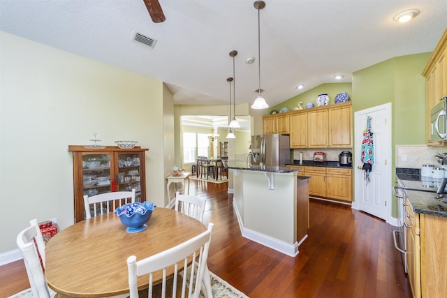 kitchen with pendant lighting, dark wood-type flooring, vaulted ceiling, decorative backsplash, and appliances with stainless steel finishes