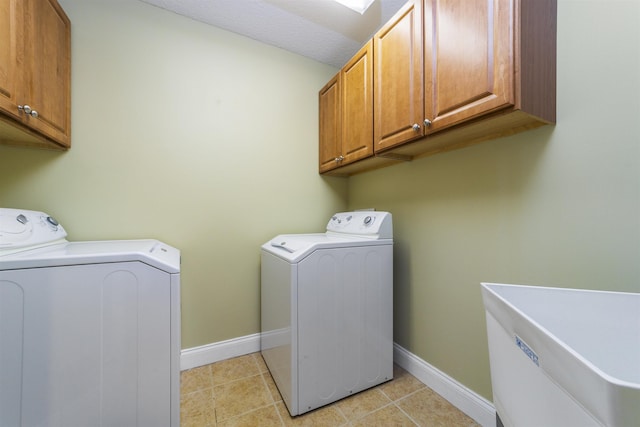 clothes washing area featuring washer and dryer, light tile patterned floors, cabinets, and sink