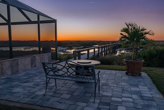 patio terrace at dusk with glass enclosure and a water view