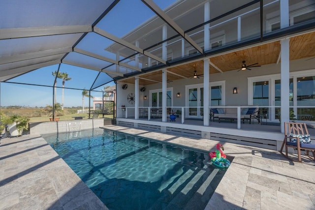 view of swimming pool with a patio, glass enclosure, and ceiling fan