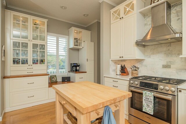 kitchen featuring wall chimney exhaust hood, white cabinetry, and high end stainless steel range