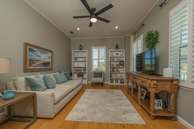 living room featuring ceiling fan, light hardwood / wood-style floors, ornamental molding, and a textured ceiling