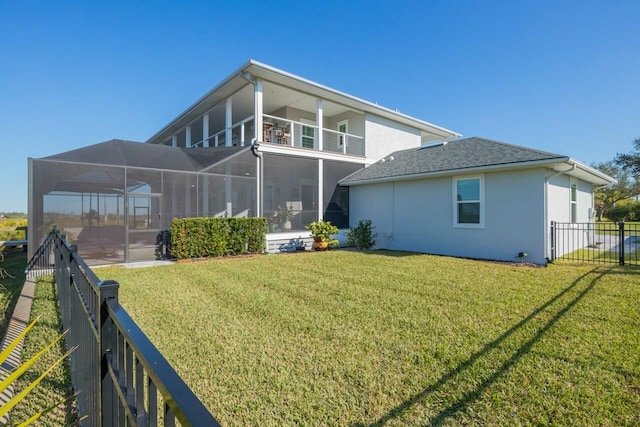 rear view of house with a lawn, glass enclosure, and a balcony