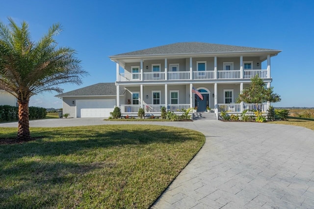 view of front facade featuring covered porch, a garage, and a front yard