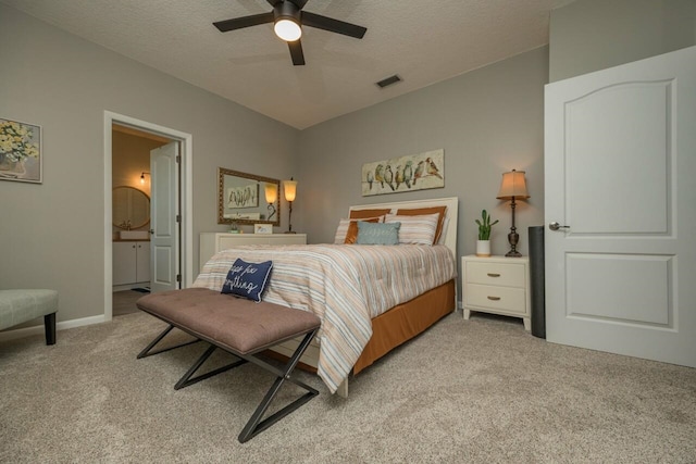 bedroom featuring ensuite bath, ceiling fan, light colored carpet, and a textured ceiling