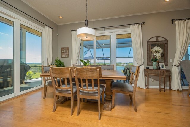 dining space featuring light hardwood / wood-style floors, ornamental molding, and a water view