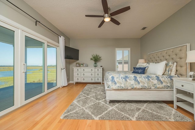 bedroom featuring access to exterior, ceiling fan, wood-type flooring, and a textured ceiling