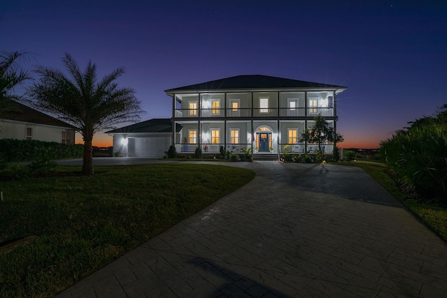 view of front facade featuring a yard, a balcony, a porch, and a garage