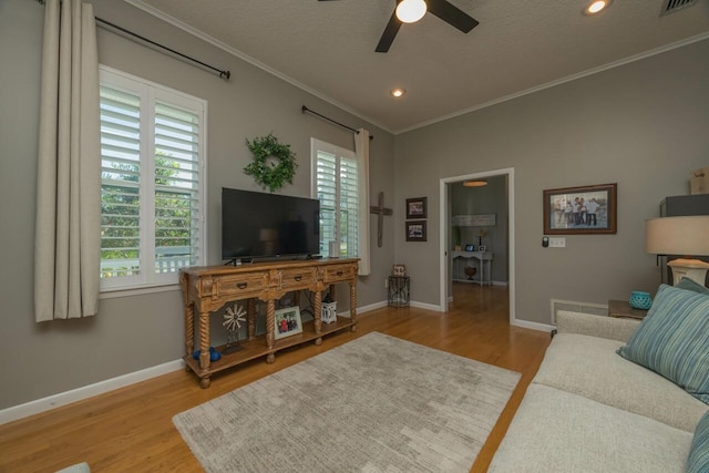 living room featuring crown molding, ceiling fan, a healthy amount of sunlight, and light wood-type flooring