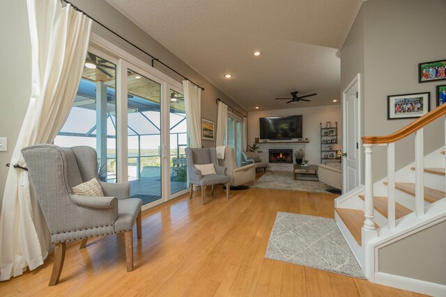 living room with ceiling fan, light wood-type flooring, a textured ceiling, and a wealth of natural light