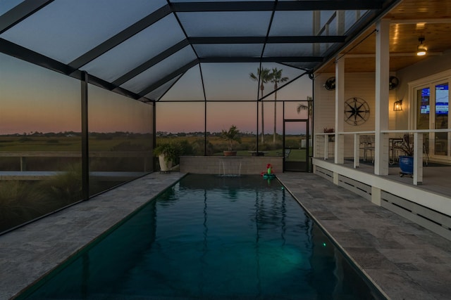 pool at dusk with a lanai and a patio area