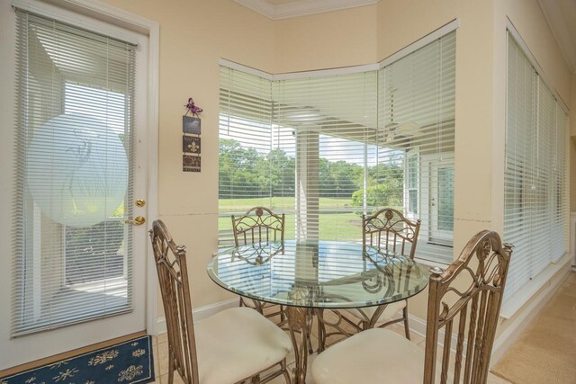 carpeted dining area with a wealth of natural light and crown molding