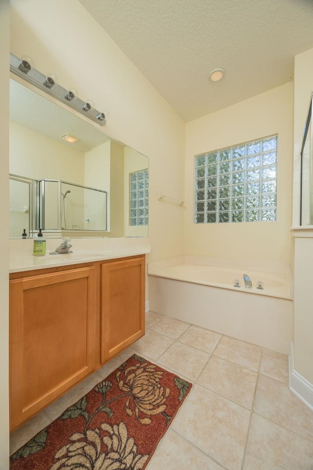 bathroom with plus walk in shower, a textured ceiling, vanity, and tile patterned floors