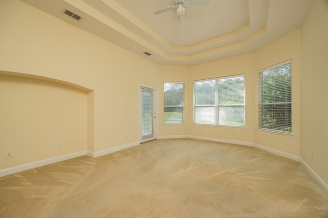 carpeted empty room with a tray ceiling and ceiling fan