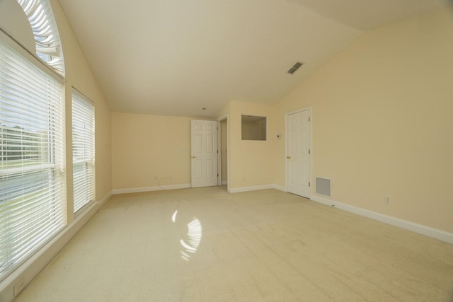 unfurnished room with light carpet, vaulted ceiling, and a healthy amount of sunlight