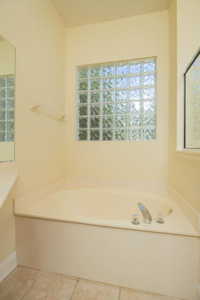 bathroom with tile patterned flooring, a wealth of natural light, and a bathing tub