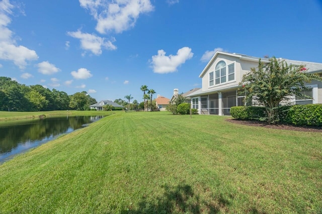 view of yard with a sunroom and a water view