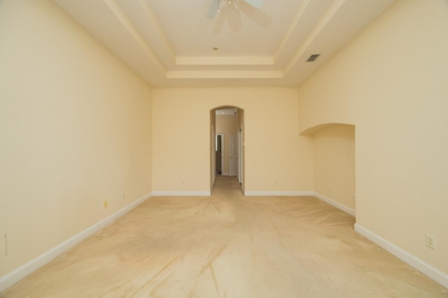 carpeted empty room featuring a tray ceiling and ceiling fan