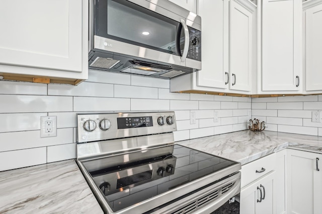 kitchen with decorative backsplash, white cabinetry, light stone countertops, and appliances with stainless steel finishes