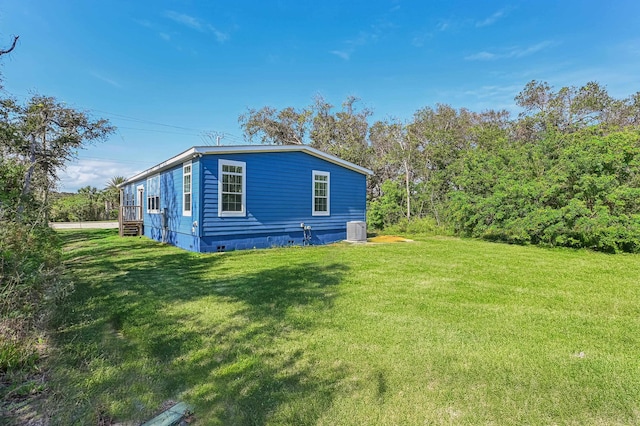 view of side of home with central AC and a yard