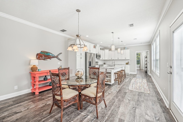 dining space with light hardwood / wood-style floors, an inviting chandelier, ornamental molding, and sink