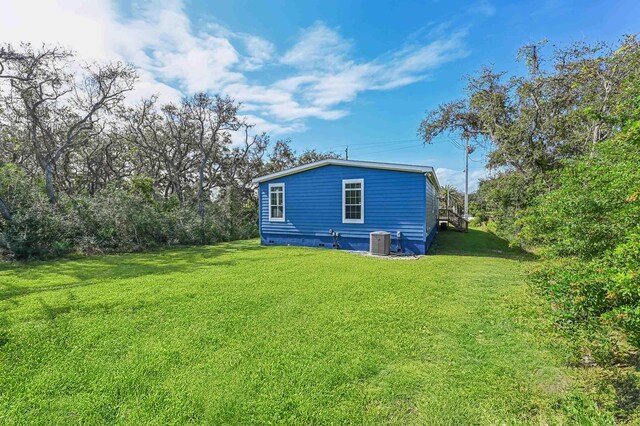 back of property featuring a yard and central AC