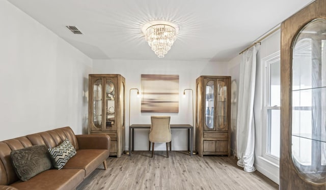 living area with light wood-type flooring and a notable chandelier