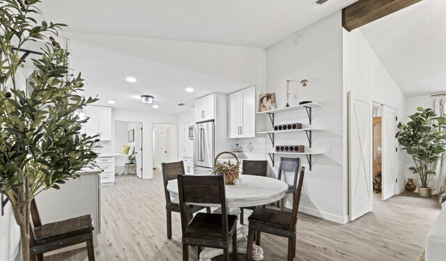 dining room featuring light hardwood / wood-style flooring and vaulted ceiling with beams