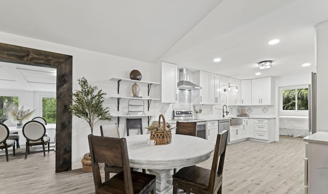 dining area with sink, light wood-type flooring, and lofted ceiling