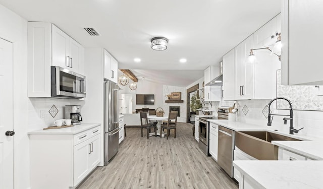 kitchen featuring appliances with stainless steel finishes, white cabinetry, tasteful backsplash, light hardwood / wood-style floors, and sink