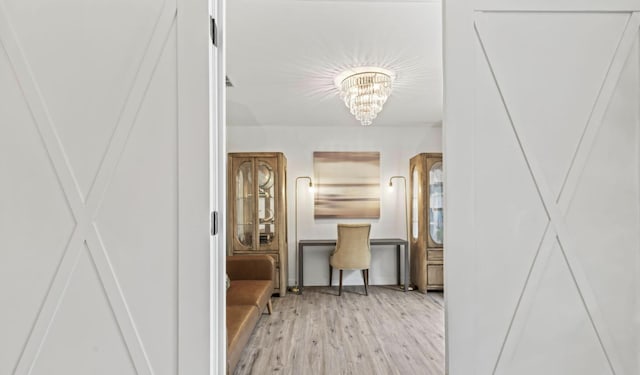 hallway with an inviting chandelier and light hardwood / wood-style flooring