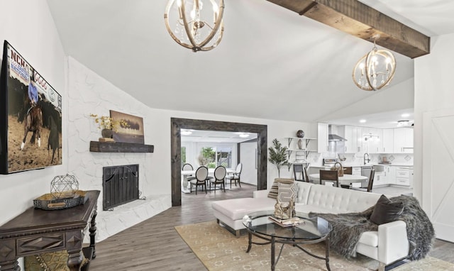 living room featuring a high end fireplace, hardwood / wood-style floors, sink, an inviting chandelier, and lofted ceiling with beams