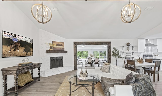 living room with a notable chandelier, vaulted ceiling, a premium fireplace, and hardwood / wood-style flooring