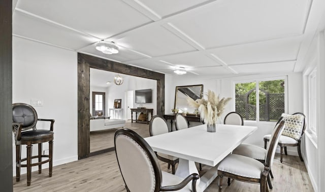 dining room featuring coffered ceiling, an inviting chandelier, and light hardwood / wood-style floors