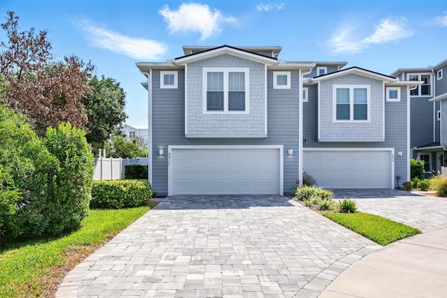 view of front of home featuring a garage, decorative driveway, and fence