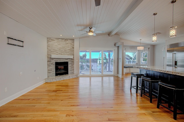 living room with lofted ceiling with beams, ceiling fan, a fireplace, and light hardwood / wood-style floors