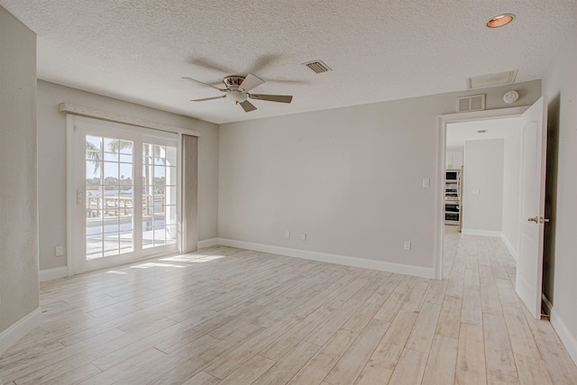 spare room with ceiling fan, light hardwood / wood-style flooring, and a textured ceiling